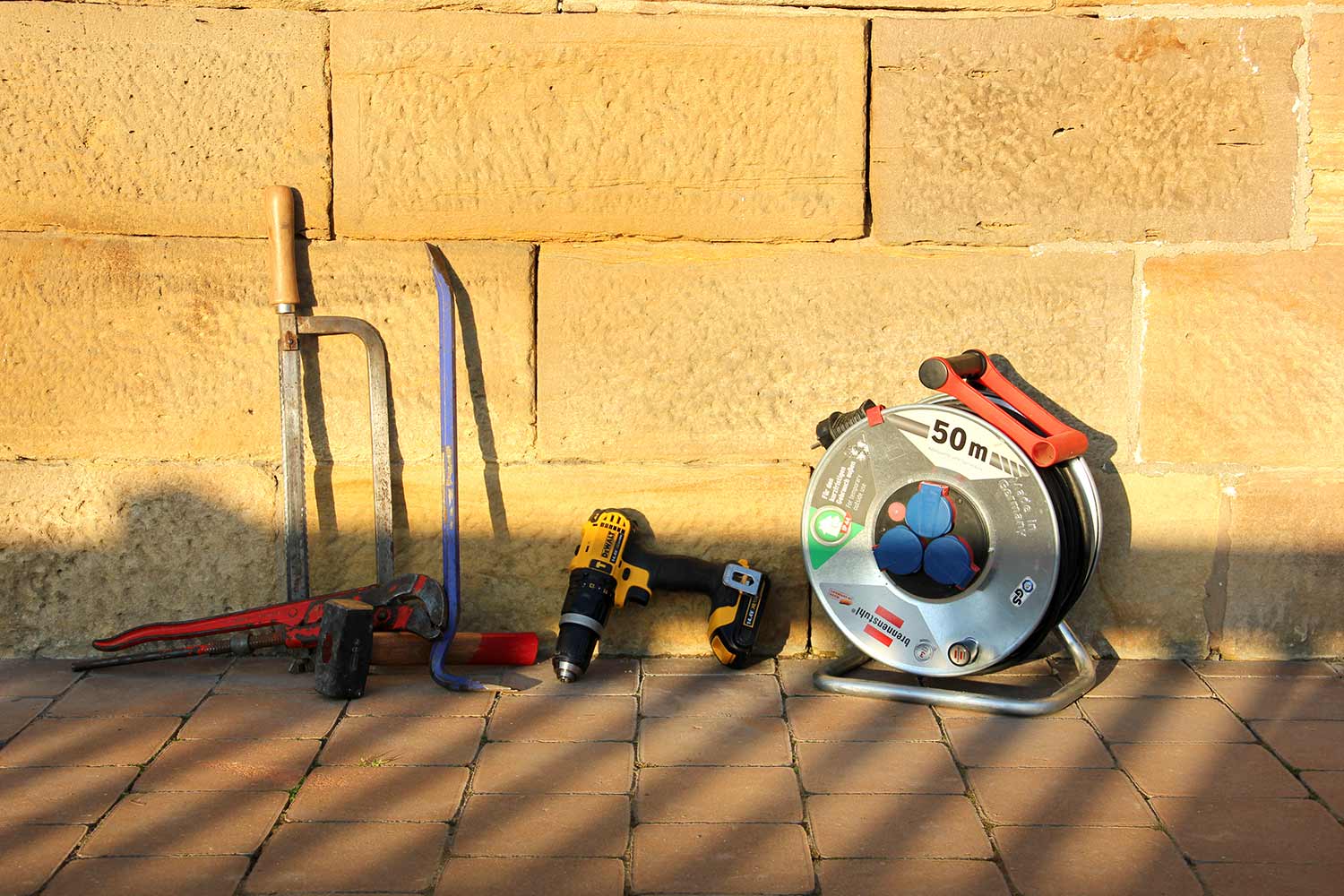 Foto: Verschiedene Bau-Werkzeuge lehnen an einer Mauer